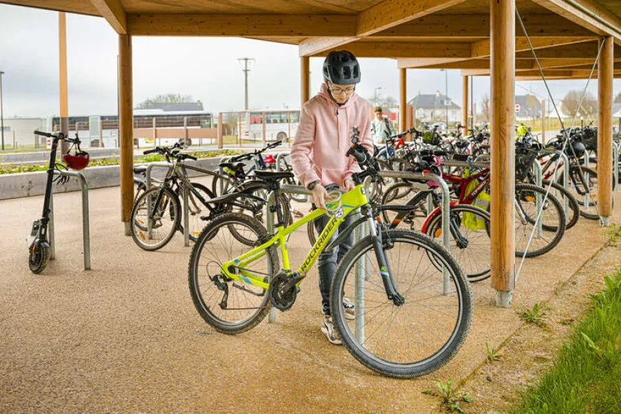 un collégien attache son vélo sous un abri