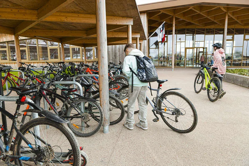 Des collégiens laissent leur vélo sous un abri dans le collège.
